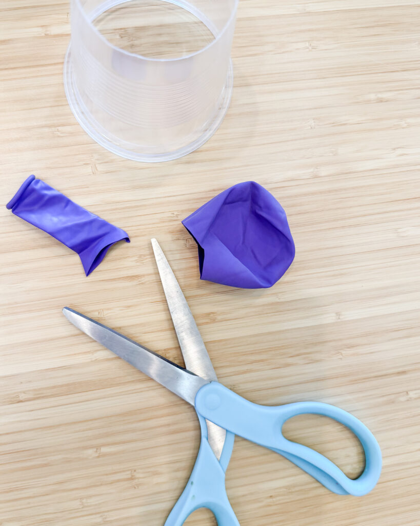 Picture show a scissors cutting a balloon for this DIY project.
