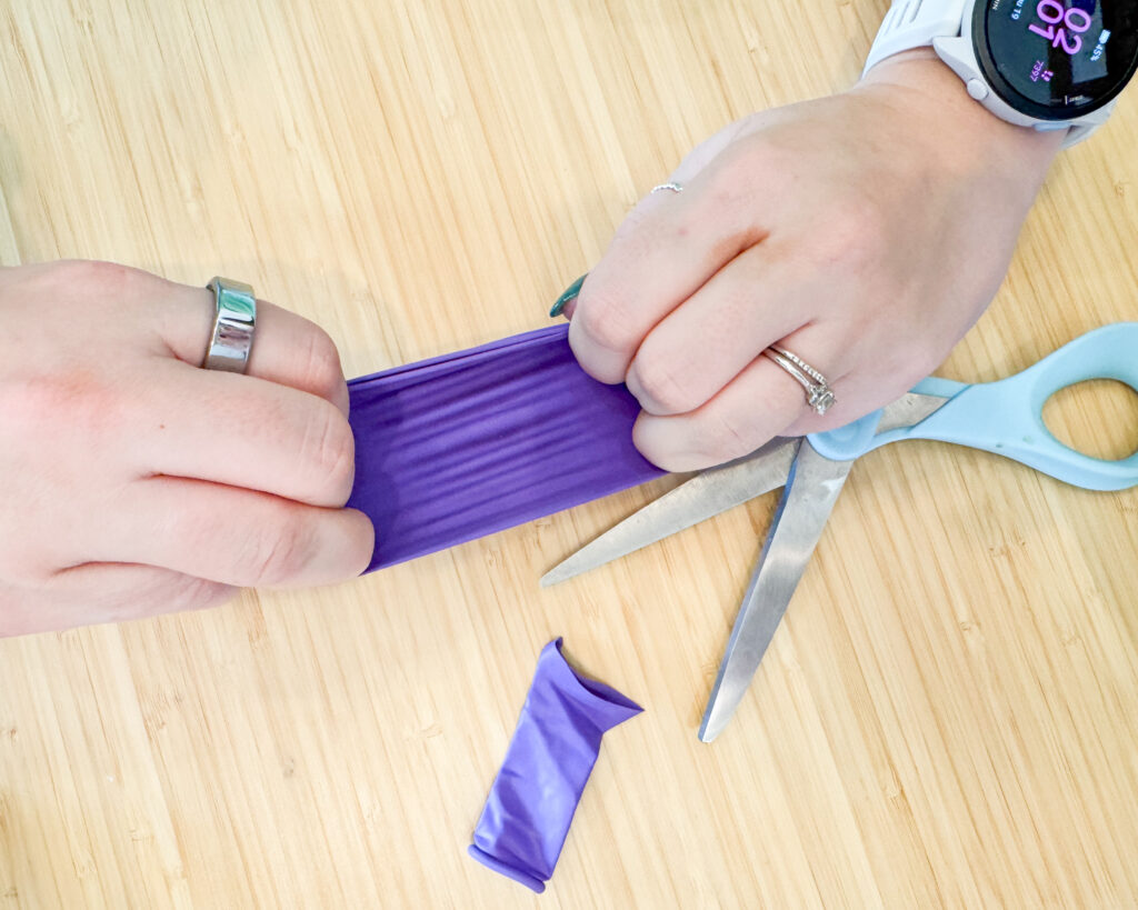 Picture shows hands stretching the balloon so the balloon can stretch over the cup.